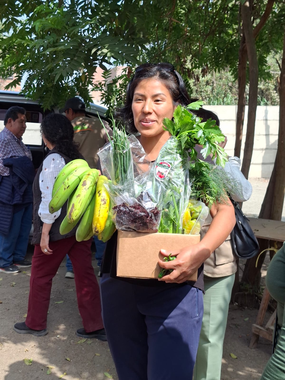 Visitante sosteniendo una caja con frutas, verduras y hierbas